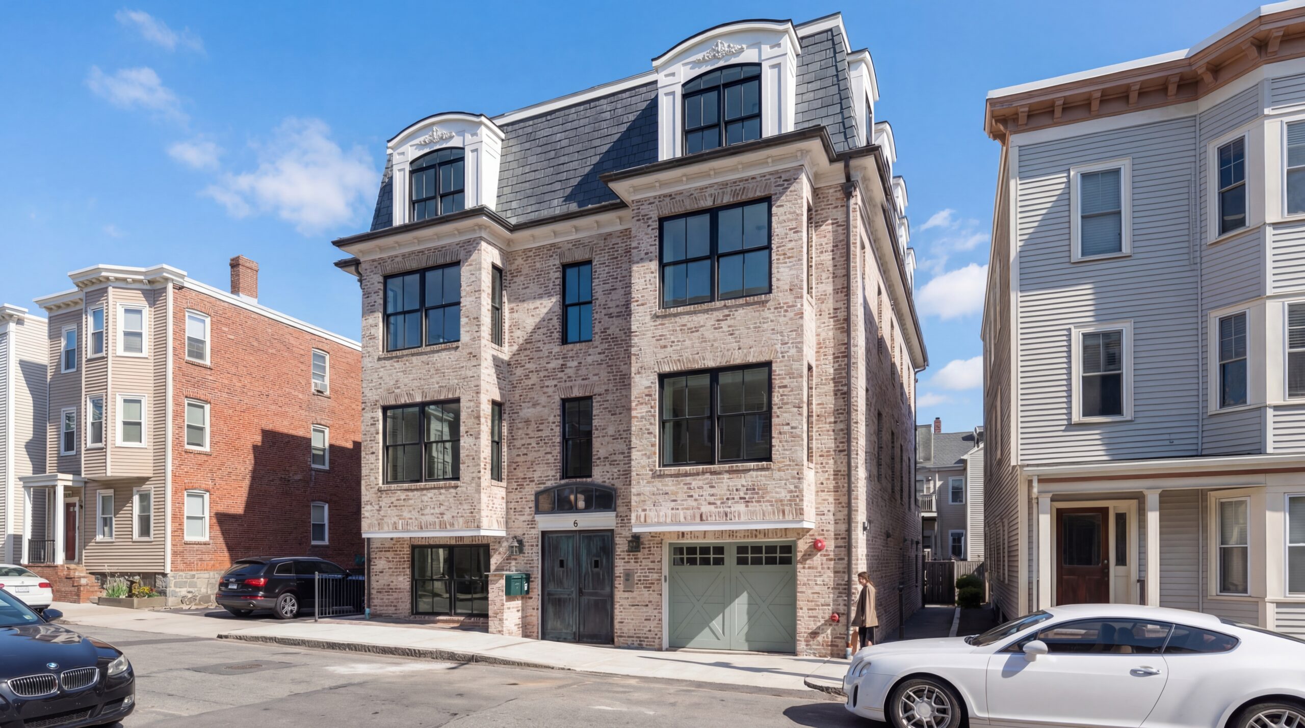 Three-story brick residential building with mansard roof, dormers, and black-framed windows