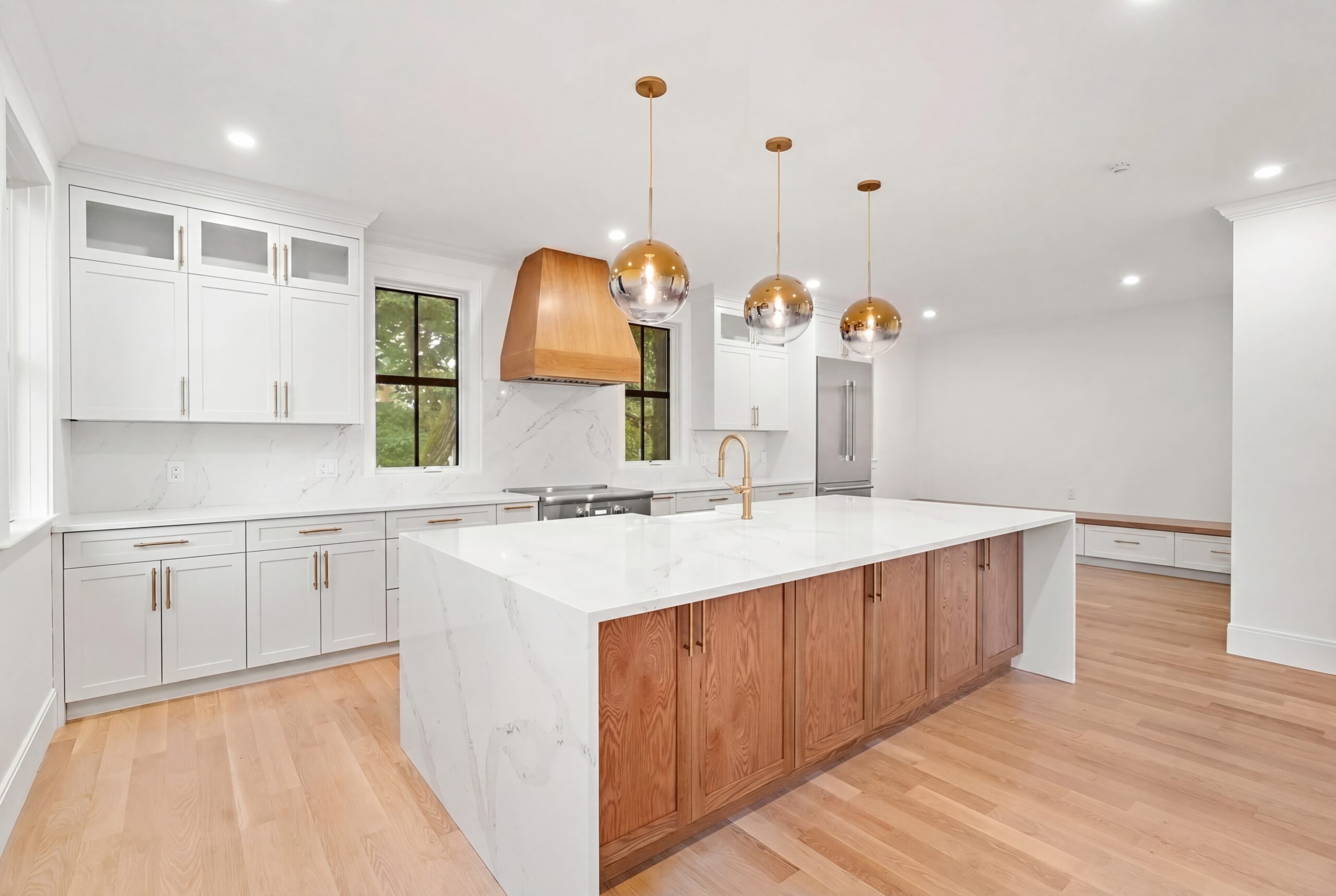 365 Worcester St - Kitchen Bright kitchen with large waterfall island, wood cabinetry, brass pendant lights, and white cabinets