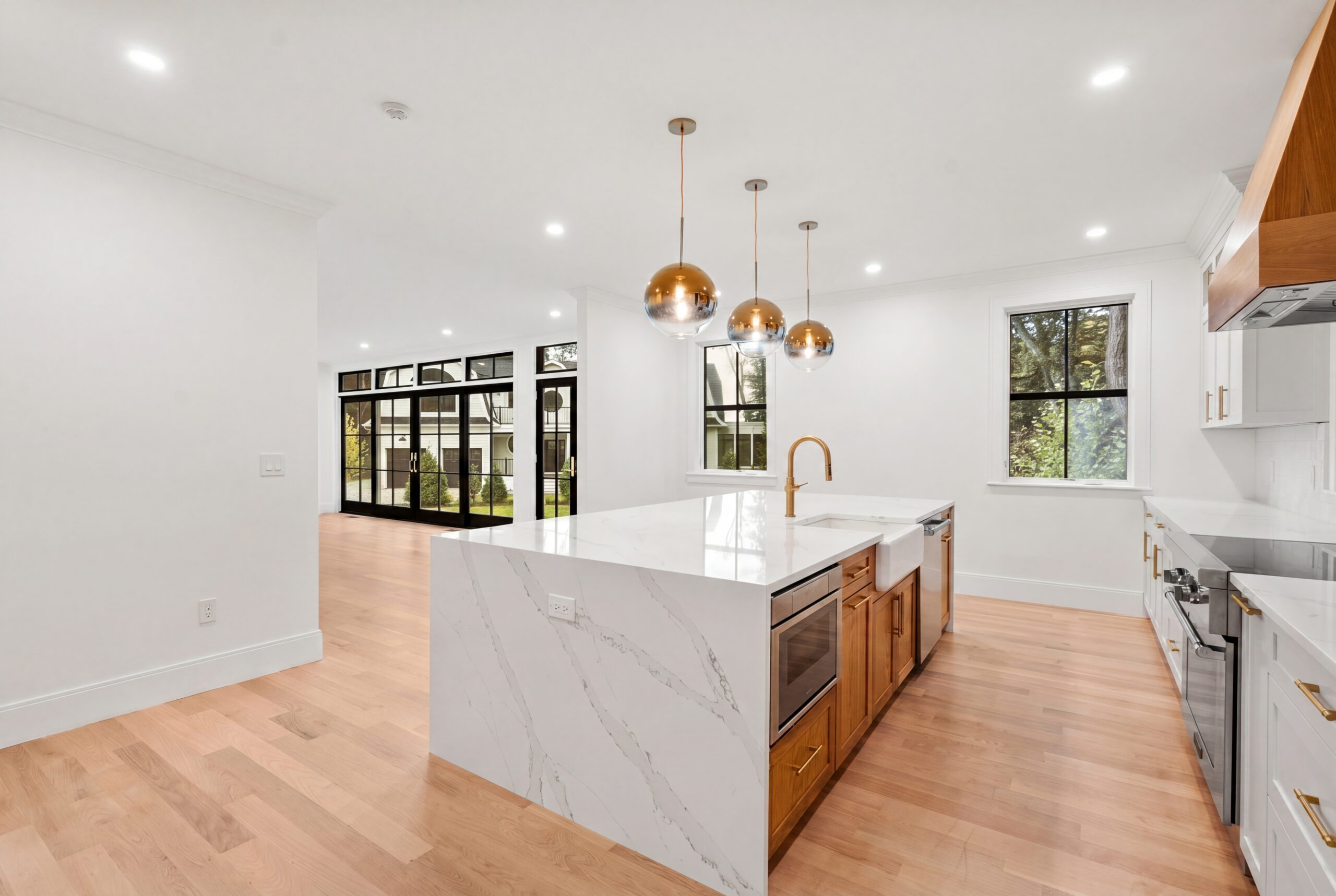 365 Worcester St - Kitchen Open kitchen with waterfall island, brass pendant lights, and black-framed glass doors leading to outdoor space