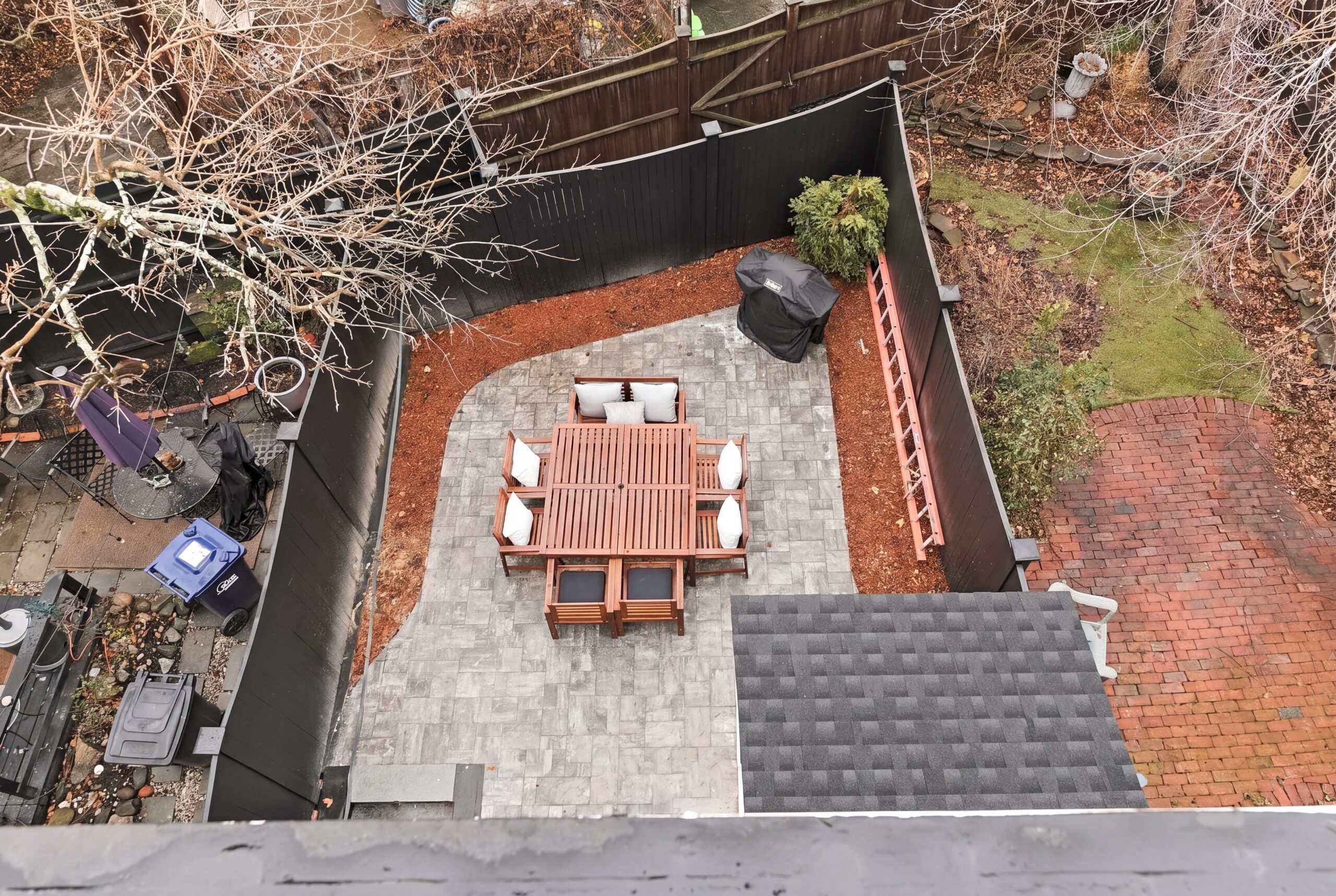 Private South Boston backyard renovation with stone patio, outdoor dining area, black privacy fencing, and landscaped urban outdoor living space.<br />
