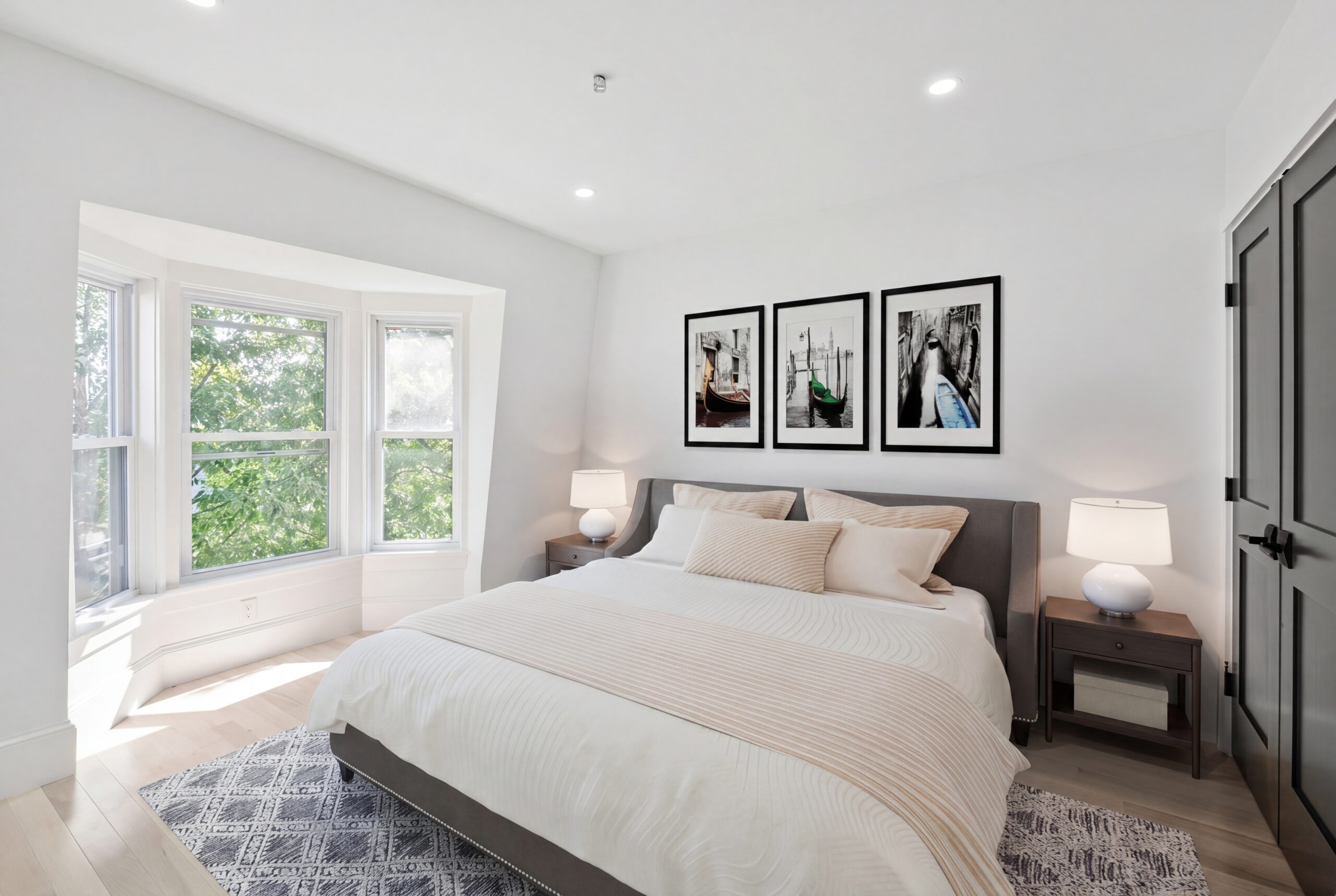 Bright modern bedroom in a renovated South Boston multifamily home featuring bay windows, contemporary finishes, and minimalist interior design.<br />
