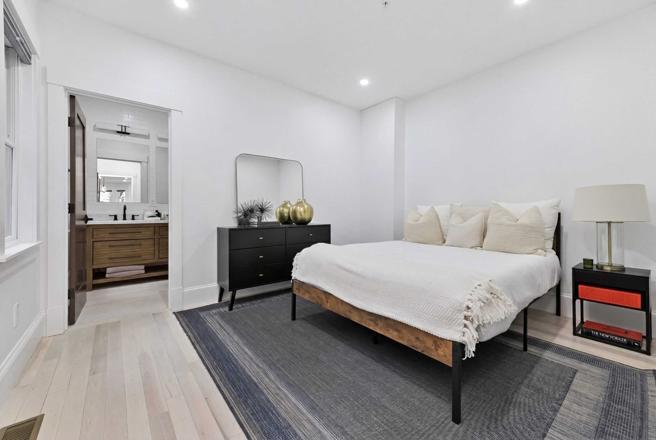 Modern primary bedroom in a renovated South Boston multifamily home featuring minimalist interiors, light wood flooring, and ensuite bathroom access.<br />

