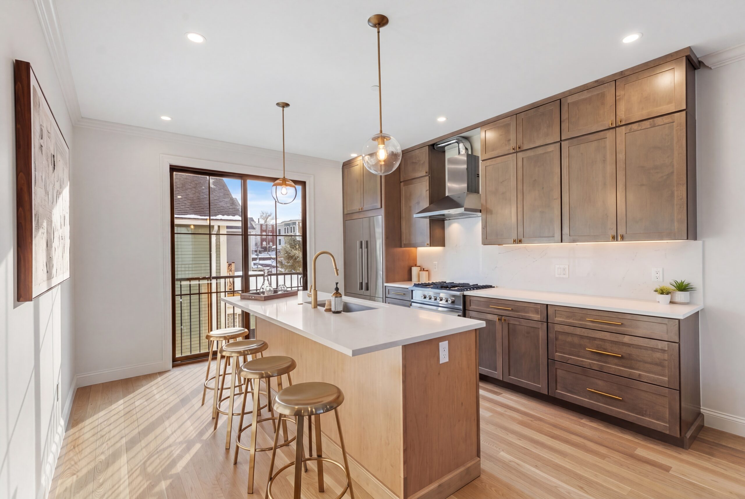 Contemporary kitchen in Boston multifamily residence with natural wood cabinetry, oversized island, and modern brass accents<br />
