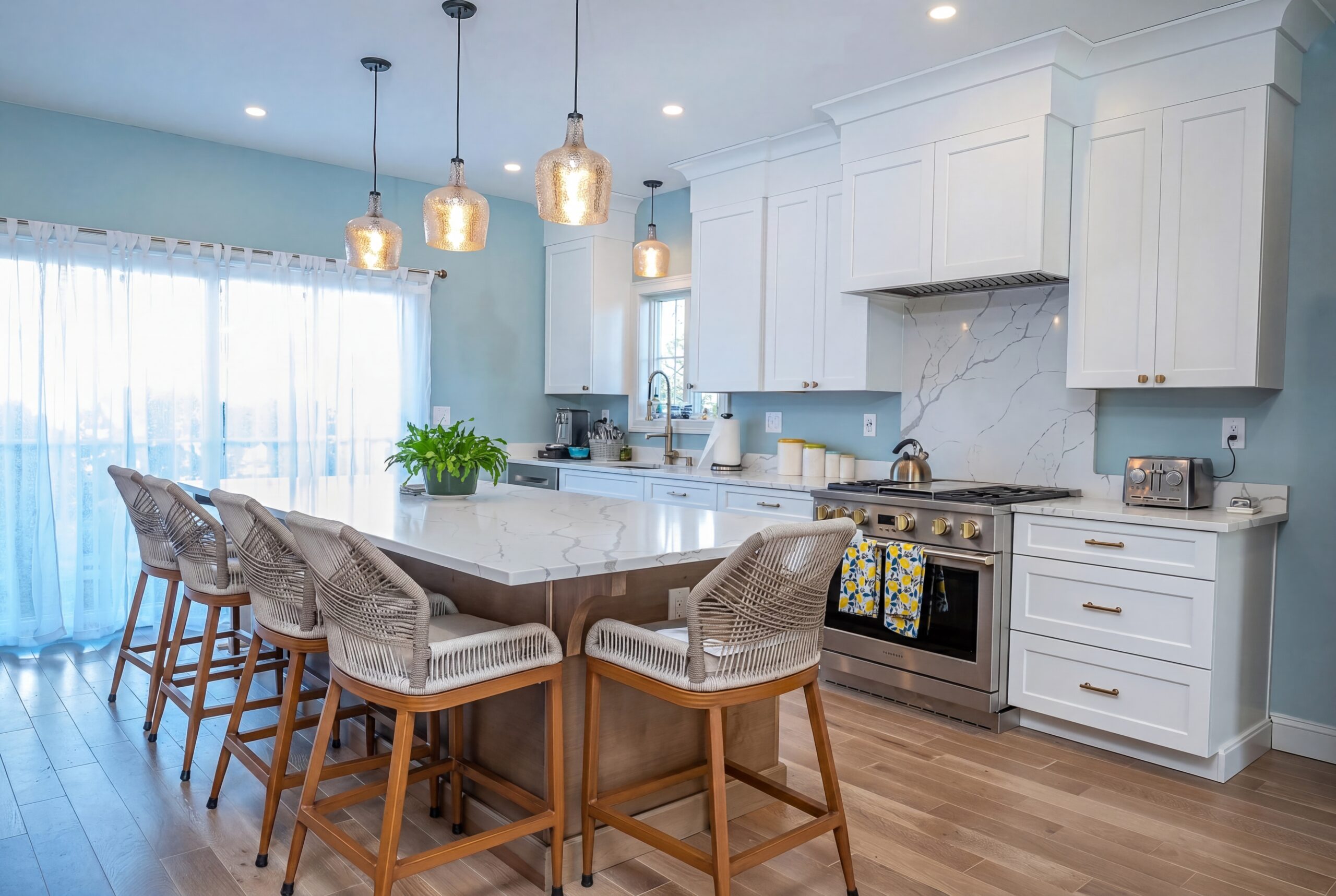 Coastal-inspired kitchen with oversized waterfall island, custom white cabinetry, and soft blue finishes in a luxury single-family residence<br />
