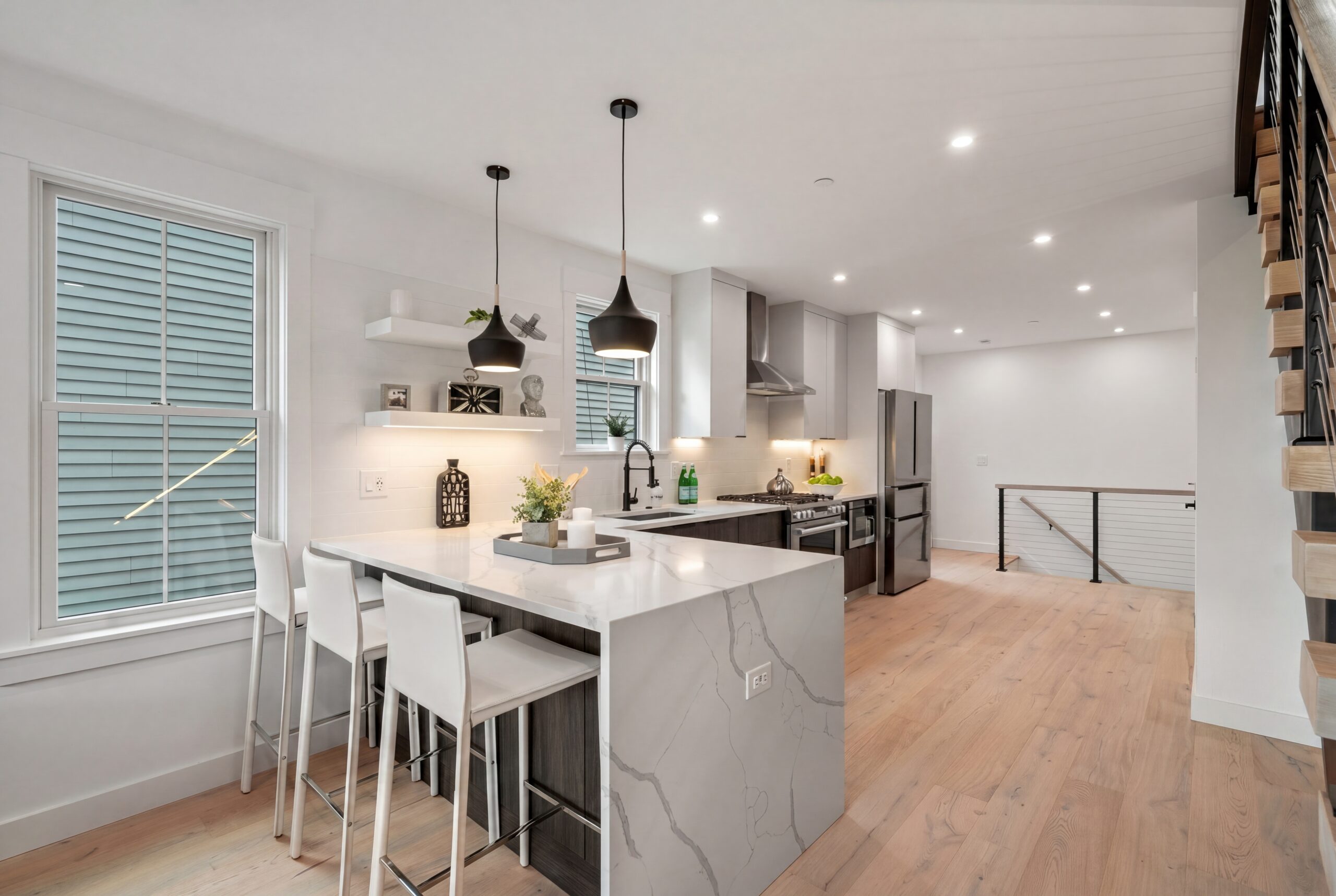 Athens St_Kitchen Contemporary kitchen interior within a modern multifamily residence, featuring a waterfall marble island with integrated seating, dark wood cabinetry, stainless steel appliances, and minimalist pendant lighting. Light oak flooring, open-concept planning, and clean modern detailing create a bright and refined urban living environment designed for contemporary city living.<br />