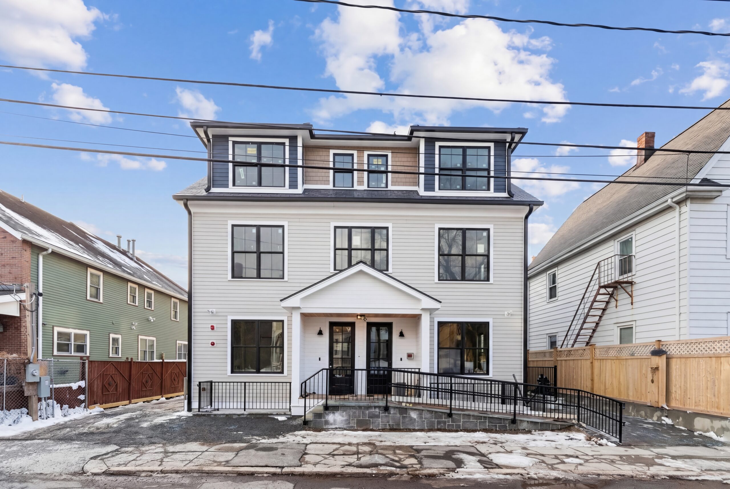 Modern three-story multifamily residential building exterior in Boston with symmetrical façade and dormer windows