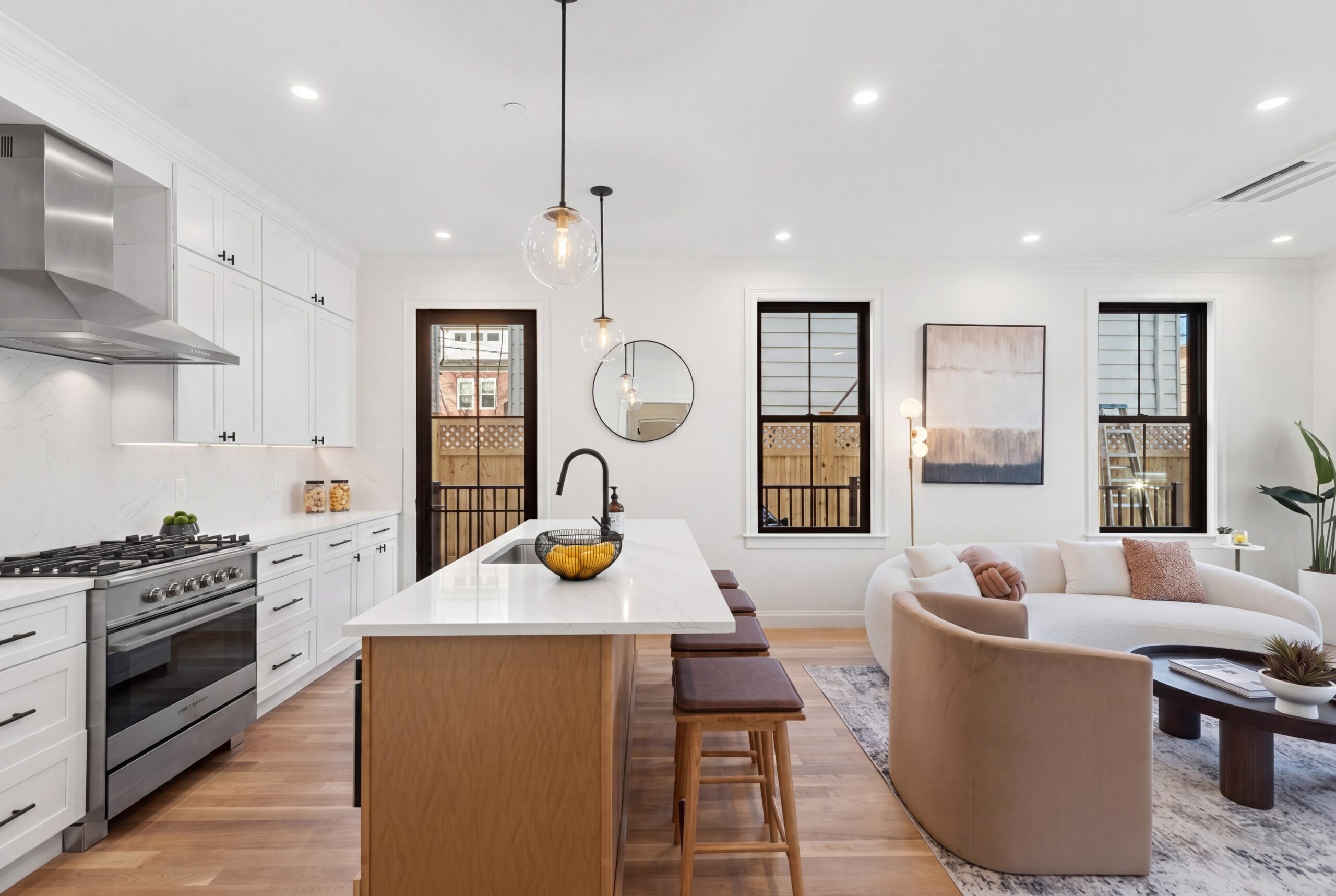 Contemporary open-concept kitchen and living space in Boston multifamily residence with white cabinetry, waterfall island, and modern finishes<br />
