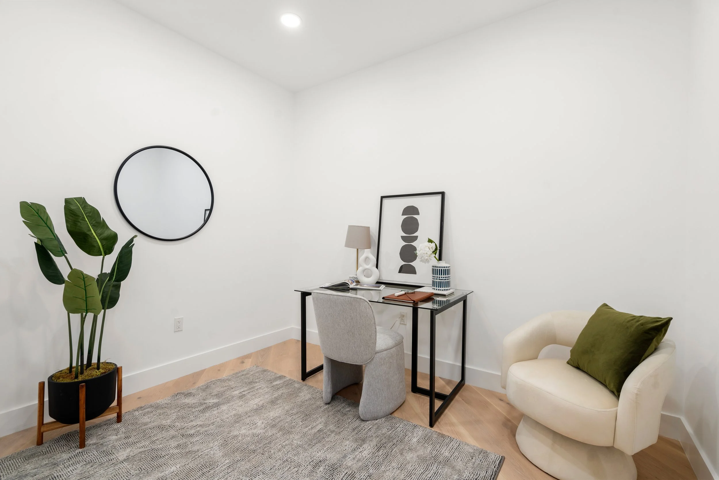 Minimal home office with desk, upholstered chair, round mirror, and accent seating