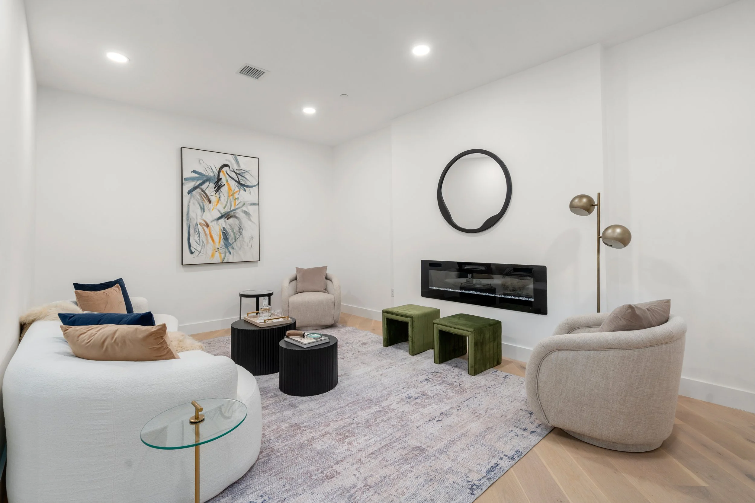 Contemporary living room with curved sofa, wall-mounted fireplace, accent chairs, and abstract artwork