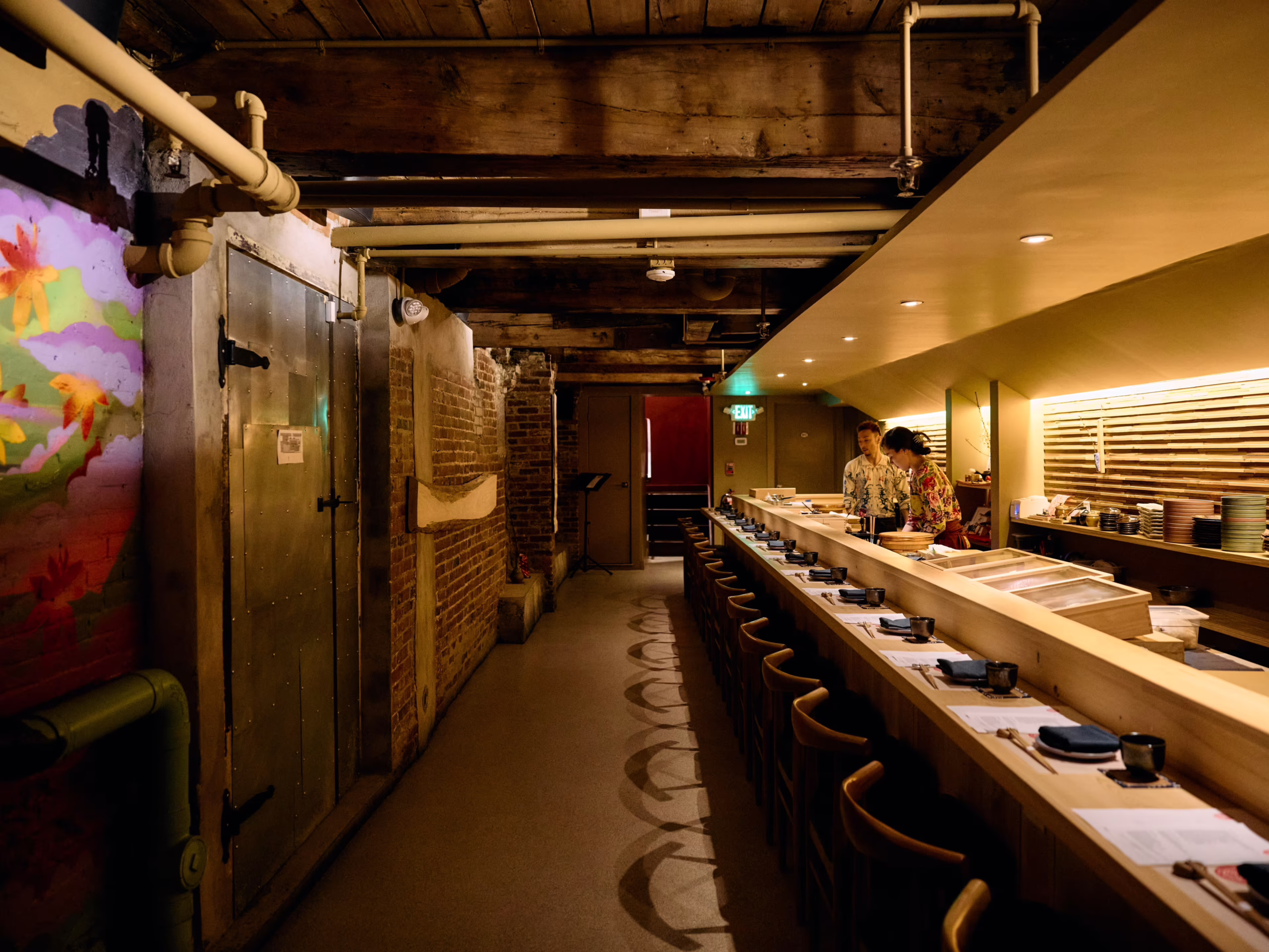 Warmly lit sushi den interior featuring a custom Hinoki wood omakase counter, minimalist seating, and refined Japanese-inspired detailing designed for an intimate dining experience.<br />

