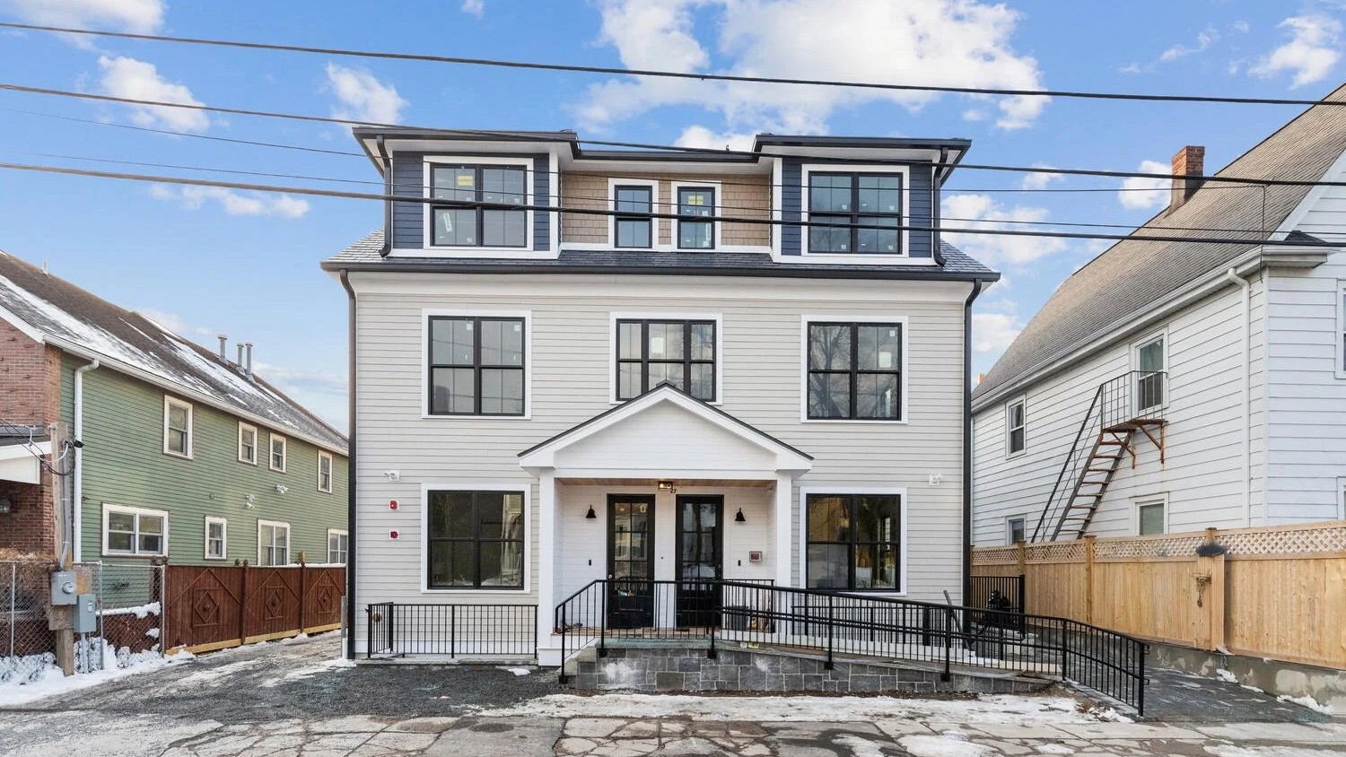 Modern three-story multifamily residential building exterior in Boston with symmetrical façade and dormer windows