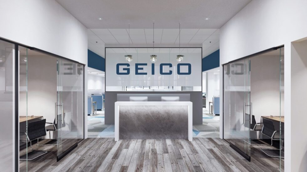 Modern Geico office reception area in Saugus, MA featuring glass meeting rooms, contemporary workplace interiors, branded design elements, and open office layout.